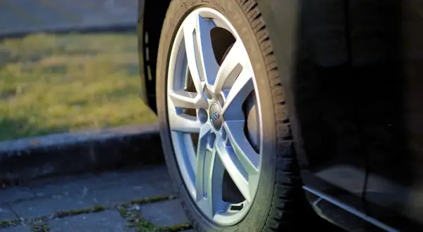 Zbliżenie na felgę aluminiową samochodu z widocznym logo Audi.