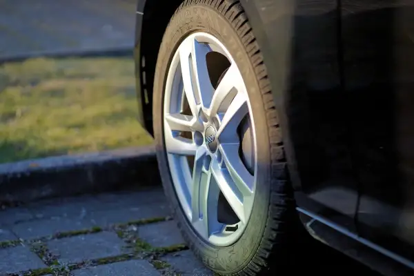 Zbliżenie na felgę aluminiową samochodu z widocznym logo Audi.